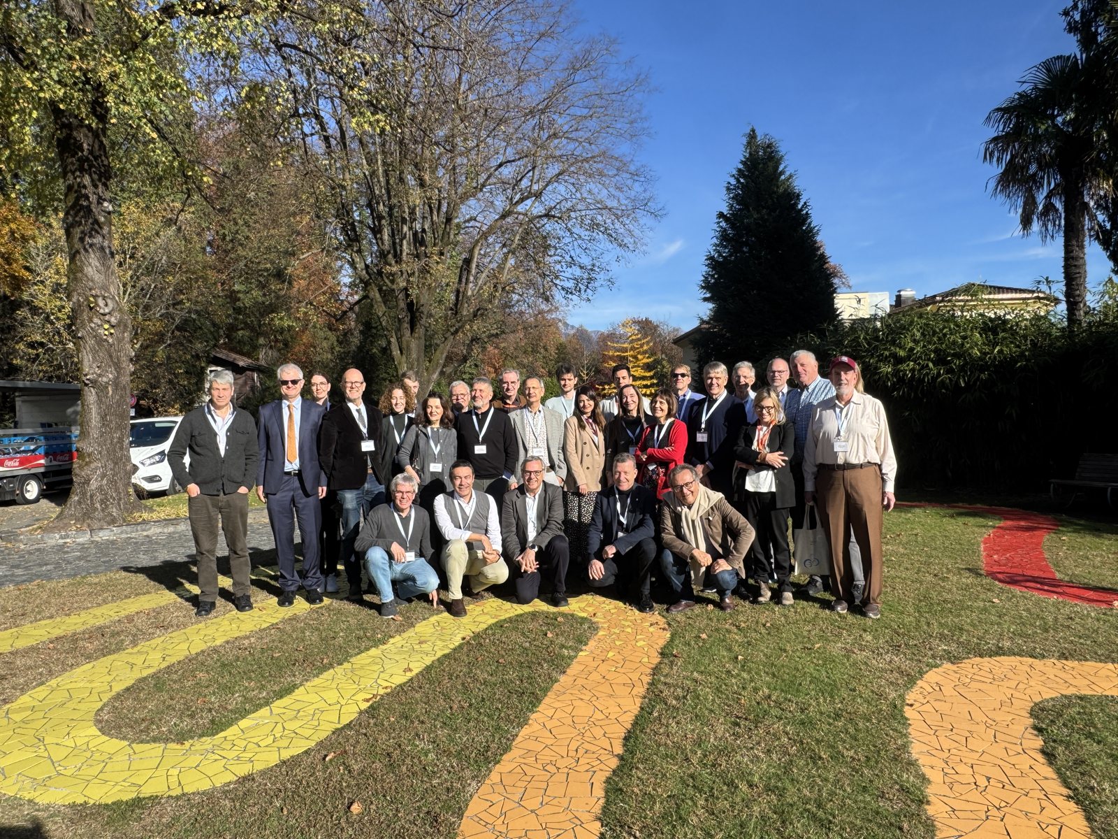 I partecipanti del convegno riuniti nel parco di Monte Verit&agrave;, sul mosaico giallo e rosso