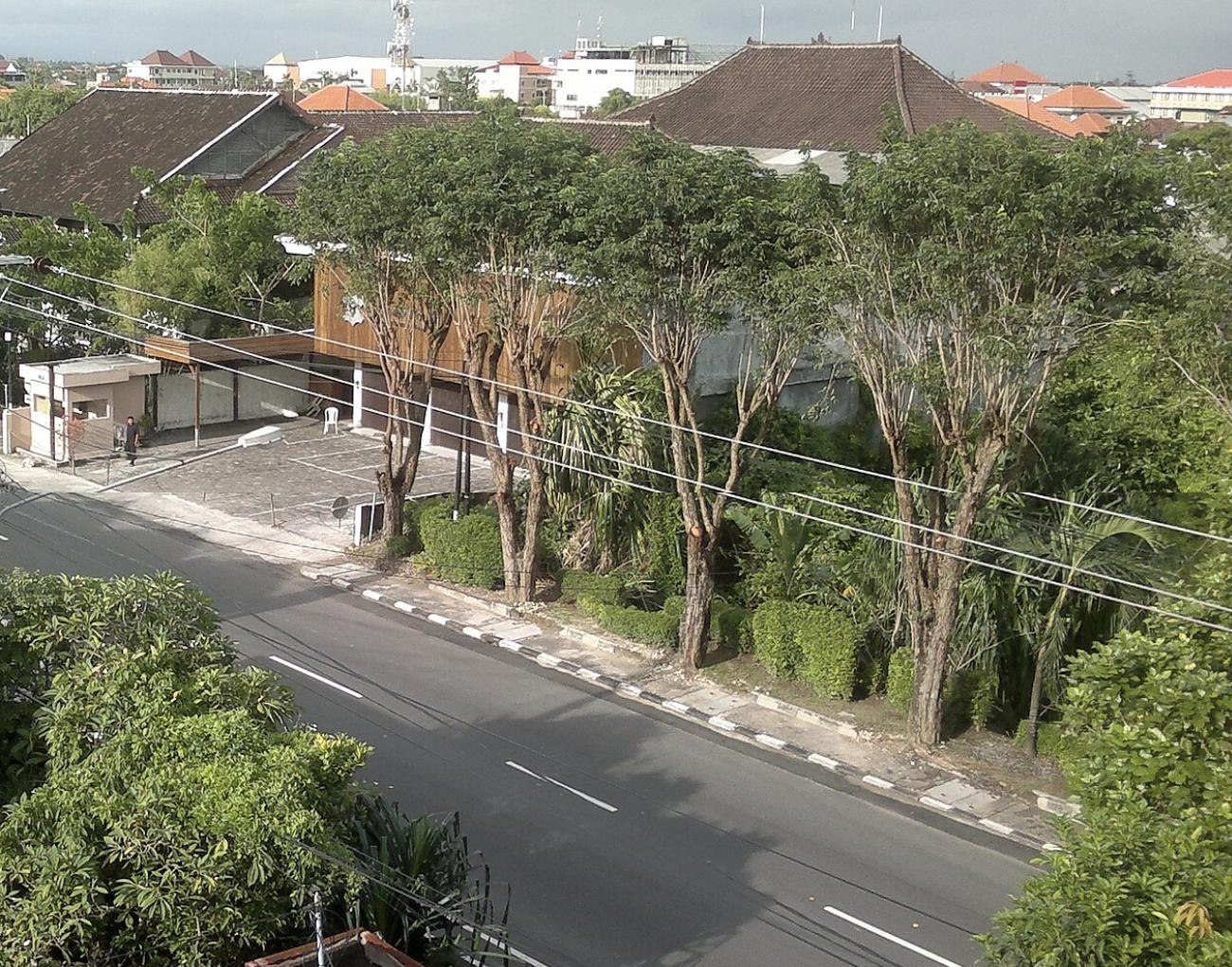 Eine menschenleere Strasse in Kuta, Bali, während des Nyepi 2012: leere Fahrbahn, Bäume und Dächer, keine Fahrzeuge.